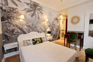 a bedroom with a bed and a wall mural of palm trees at Hôtel Chopin in Paris