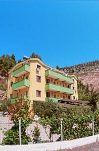 a yellow building with green balconies on a hill at Hotel Bolonja in Shëngjin