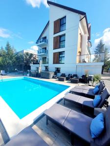 a swimming pool with lounge chairs and a building at Apartamenty Dolce Vita in Ostrowo
