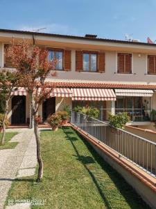 une maison avec une clôture et un arbre dans la cour dans l'établissement Villetta Camelia, à Guamo