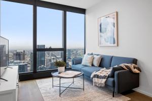 sala de estar con sofá azul y ventanas grandes en CLLIX Australia 108 Apartments, en Melbourne