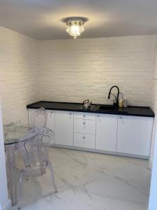 a kitchen with white cabinets and a sink and a chair at White Apartment in Elblag