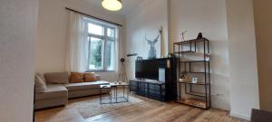 a living room with a couch and a television at Entre 2 Ourthes in La Roche-en-Ardenne