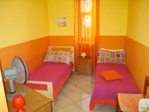 サン・ジョルジョにあるCasa Rosariaのベッド2台、テーブル、ファンが備わる客室です。