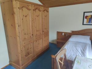 バート・アウスゼーにあるApartment Familie Hauptのベッドルーム1室(ベッド1台付)、木製キャビネットが備わります。