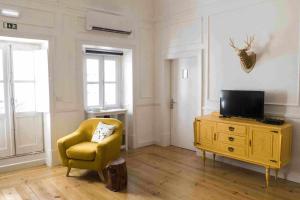 a living room with a yellow chair and a television at Patinha Inn in Évora