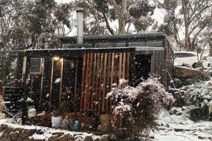 un pequeño cobertizo cubierto de nieve en un patio en ReThynk Unique Tiny home East Jindabyne, en Jindabyne