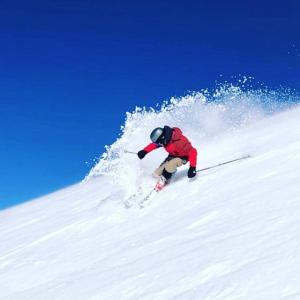 a person is skiing down a snow covered slope at ReThynk Unique Tiny home East Jindabyne in Jindabyne