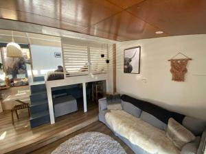 a living room with a couch and a bedroom at ReThynk Unique Tiny home East Jindabyne in Jindabyne