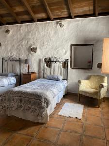 a bedroom with a bed and a chair and a tv at Finca Los Ciruelos Casas Rurales in Icod de los Vinos