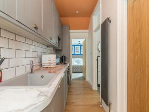 a kitchen with a large white sink and a hallway at Stylish 2-bedroom flat with patio and garden in Brighton & Hove