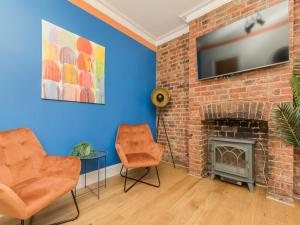 ein Wohnzimmer mit einem gemauerten Kamin und orangefarbenen Stühlen in der Unterkunft Stylish 2-bedroom flat with patio and garden in Brighton & Hove