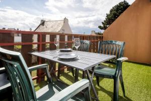 a table with chairs and wine glasses on a balcony at Appartement neuf style industriel *** proche de la mer in Roscoff