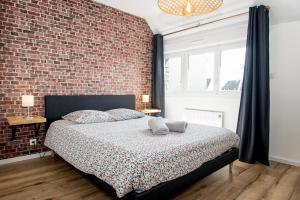 um quarto com uma parede de tijolos e uma cama em Appartement neuf style industriel *** proche de la mer em Roscoff