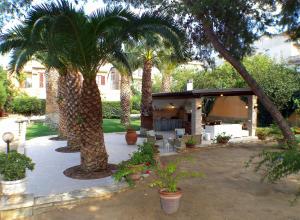 a courtyard with palm trees and a house at BB DoliaHouse in Dolianova