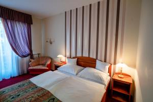 a hotel room with a bed and a chair at Hotel Erzsébet in Hévíz