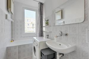 a white bathroom with a sink and a washing machine at Wave Apartments - ŻUŁAWIANKA GDAŃSK in Gdańsk