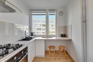 a kitchen with two stools in front of a counter at Wave Apartments - ŻUŁAWIANKA GDAŃSK in Gdańsk