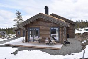 a log cabin with a deck with a table and chairs at Trysilsetra 35 in Trysil