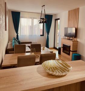 un soggiorno con tavolo, sedie e TV di NEO Apartman a Zlatibor