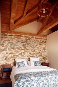 a bedroom with a bed and a stone wall at L'aube des Fourniels in Malbosc