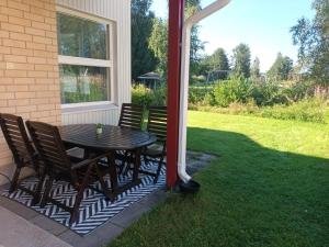 a patio with a table and chairs on a lawn at Puistokatti Apartment in Vuokatti