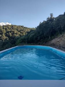 una piscina di acqua blu con una montagna sullo sfondo di Yogaville Sardegna a Luras