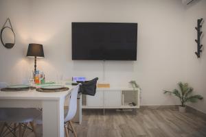 ein Raum mit einem Tisch und einem Fernseher an der Wand in der Unterkunft Acogedor apartamento en Triana in Sevilla