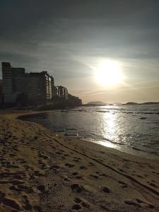 a beach with the sun shining on the water at Pousada Família Guarapari in Guarapari