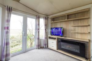 a living room with a fireplace and a tv at 6 Berth Caravan For Hire At Seawick Holiday Park By The Beach Ref 27011hv in Clacton-on-Sea