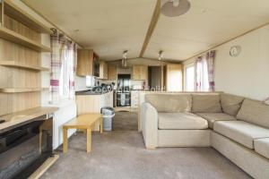 a living room with a couch and a kitchen at 6 Berth Caravan For Hire At Seawick Holiday Park By The Beach Ref 27011hv in Clacton-on-Sea
