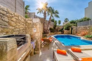 a backyard with a swimming pool and a stone wall at Djar ta Menzja 2 Holiday Home in Sannat