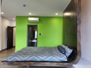 sypialnia z zieloną ścianą i łóżkiem w obiekcie Tom Homestay Quy Nhơn w mieście Quy Nhơn