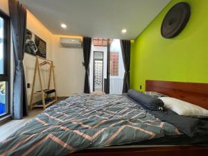um quarto com uma cama com uma parede verde em Tom Homestay Quy Nhơn em Quy Nhon