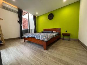 a bedroom with a bed and a green wall at Tom Homestay Quy Nhơn in Quy Nhon