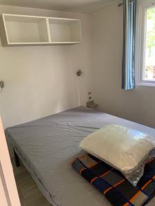 a bed in a white room with a window at Mobil home 6 personnes camping 4* Mimizan in Aureilhan