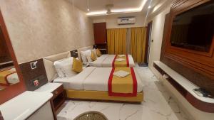a hotel room with two beds and a television at Hotel Manila in Siliguri