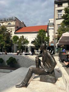 Eine Statue eines Mannes, der auf einer Bank sitzt. in der Unterkunft Cvetni trg in Belgrad