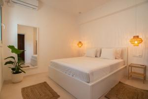 The Suite Athens في أثينا: غرفة نوم بيضاء مع سرير أبيض ومرآة