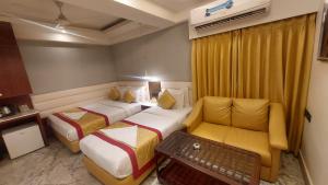 a hotel room with two beds and a couch at Hotel Manila in Siliguri