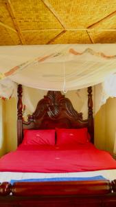 ein Himmelbett mit roten Kissen im Schlafzimmer in der Unterkunft Sina Village in Mpigi