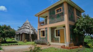 uma pequena casa com telhado de palha em Sina Village em Mpigi