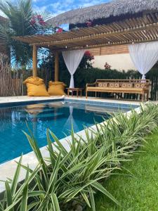 a swimming pool with a pergola and a bench at Vila Gará Kite House - Ilha do Guajiru in Itarema