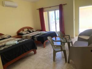 Zimmer mit 2 Betten und Stühlen sowie einem Fenster in der Unterkunft Punta Rucia Cristal Beach in Punta Rucia
