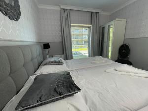 a bedroom with a large white bed with a window at Apartament Luxury 5 Mórz in Sianozety
