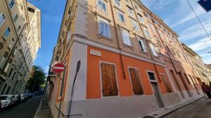 un edificio arancione e bianco sul lato di una strada di El Quartierin a Trieste