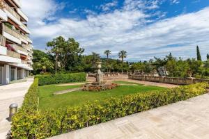 ein Park mit einem Brunnen in der Mitte eines Gartens in der Unterkunft Superbe 3 pièces avec piscine et tennis in Cannes