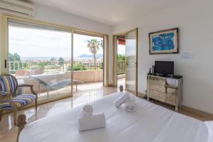 ein Schlafzimmer mit einem großen weißen Bett und einem Balkon in der Unterkunft Superbe 3 pièces avec piscine et tennis in Cannes
