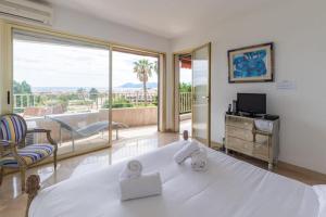 a bedroom with a large white bed and a balcony at Superbe 3 pièces avec piscine et tennis in Cannes