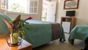 a room with a green bed and a vase with flowers on a table at Pousada Tartaruga in Búzios